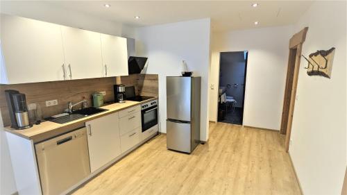 a kitchen with white cabinets and a stainless steel refrigerator at Ferienhaus Wetterstein in Grainau
