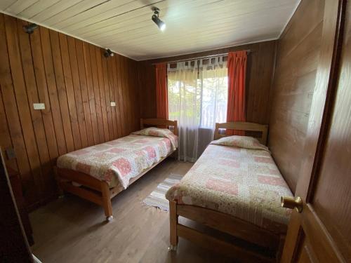 two beds in a small room with a window at Hostal el Nogal Pucón in Pucón