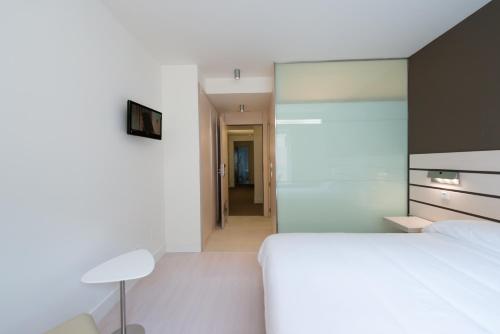 a bedroom with a large white bed and a hallway at Hotel Boreal Viento Norte in Burgos