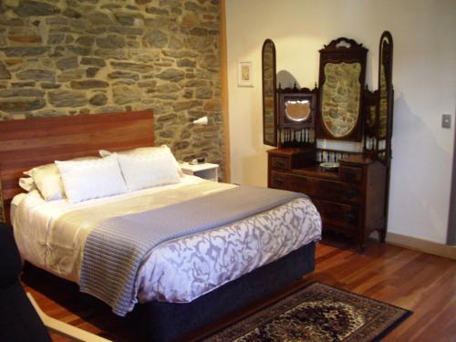 a bedroom with a bed and a stone wall at 1860 Wine Country Cottages in Springton