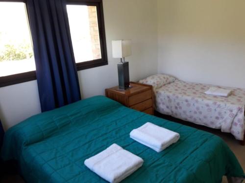 a bedroom with a green bed with two towels on it at Casa en La Cumbrecita in La Cumbrecita