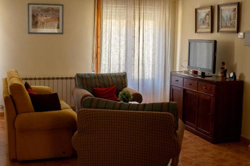 Casa Laiglesia في Uncastillo: غرفة معيشة مع كرسيين وتلفزيون بشاشة مسطحة