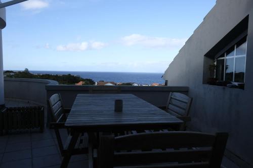 a wooden table and chairs on a balcony with the ocean at Pico Dreams in São Roque do Pico