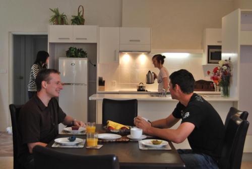 two men sitting at a table in a kitchen at Brayfield Cottage in Murray Bridge