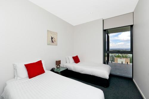 two beds in a room with a window at AAC Apartments - Manhattan in Canberra