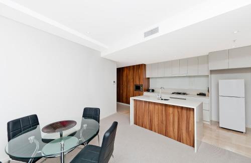 a kitchen with a glass table and black chairs at AAC Apartments - Manhattan in Canberra