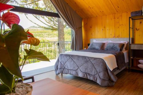 een slaapkamer met een bed en een groot raam bij Cappio Pousada e Lazer in Bento Gonçalves