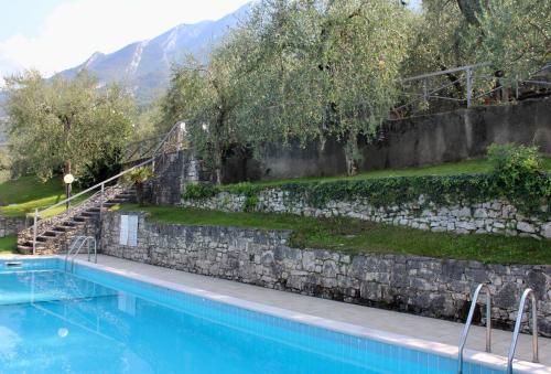 a large swimming pool with a stone wall and stairs at Appartamento Venzo in Brenzone sul Garda