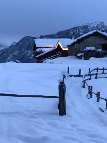 a snow covered field with a fence and a barn at Le Rascard in Valtournenche