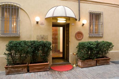 a building with two potted trees in front of a door at Albergo Delle Notarie in Reggio Emilia