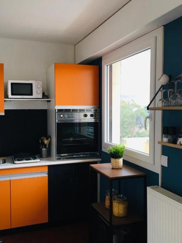 une cuisine avec des armoires orange et noire et une fenêtre dans l'établissement Bleu Salé - F2 Courseulles avec balcon, à Courseulles-sur-Mer