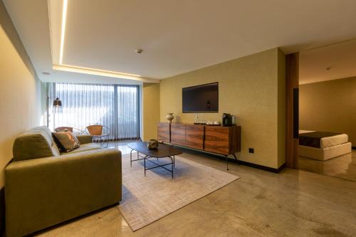 a living room with a couch and a flat screen tv at Well Hotel & Spa in Maceira