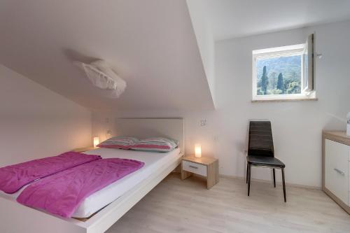 a bedroom with a bed and a chair and a window at Apartment Karin in Veli Lošinj
