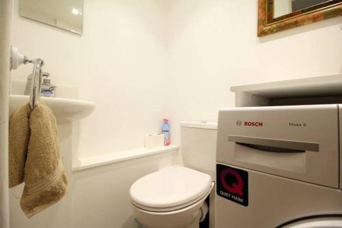 Baño blanco con aseo y lavamanos en Pebbles Apartment By Air Premier en Seaford