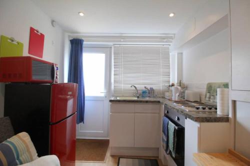 a kitchen with a red refrigerator and a window at Pebbles Apartment By Air Premier in Seaford