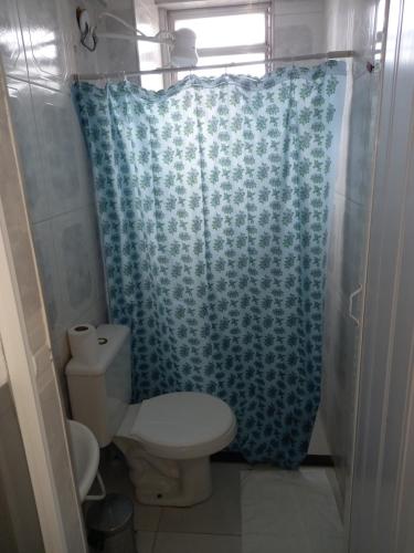 a bathroom with a toilet and a blue shower curtain at Hotel PS Itaboraí in Itaboraí