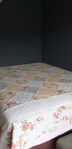 a bed with a quilt with flowers on it at Casa com Piscina e Hidromassagem Montoski in Bombinhas