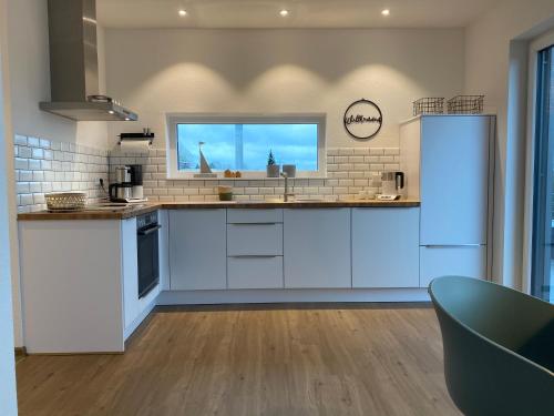 a kitchen with white cabinets and a window at Helle Dachgeschosswohnung in Bockhorn, LK Friesland in Bockhorn