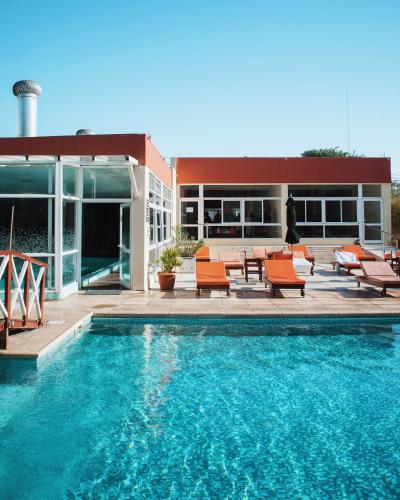 a swimming pool with orange chairs and a building at Hotel Termal Los Cardones & Spa in Termas de Río Hondo