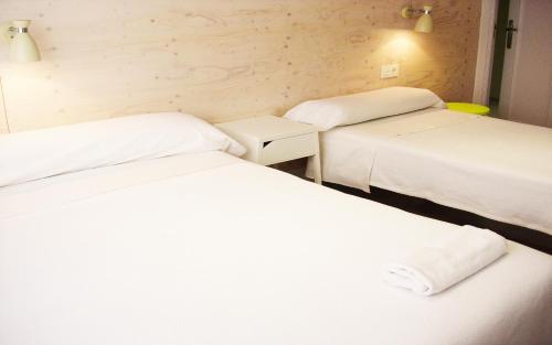 two beds in a room with white sheets at Pensión Boreal Solano in Burgos