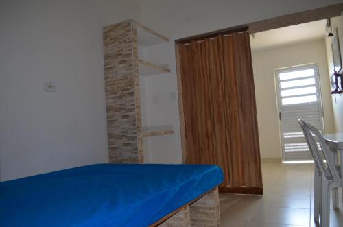 a room with a bed with a blue sheet on it at Pousada/Flat Praia Do Sonho in Itanhaém