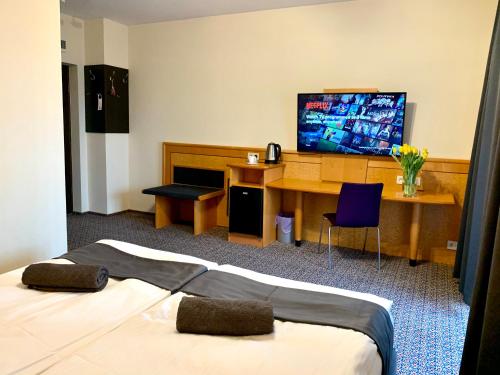 a hotel room with a bed and a desk and a television at Słupsk forest - PREMIUM APARTAMENTS - Kaszubska street 18 - Wifi Netflix Smart TV50 - pleasure quality stay in Słupsk