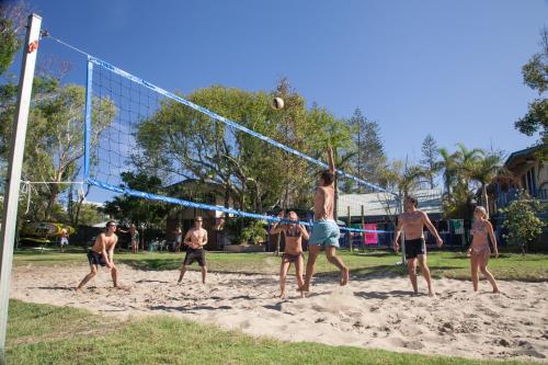a group of men playing volleyball on a beach at Backpackers Inn On The Beach in Byron Bay