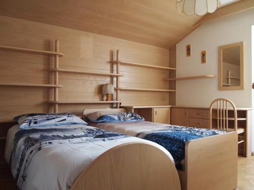 two beds in a room with wooden walls and shelves at Ciasa Giorgina in Pozza di Fassa