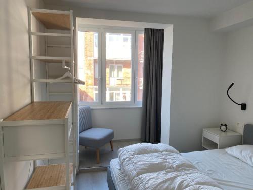 1 dormitorio con cama, escritorio y ventana en Ruim en lichtrijk appartement op 100m van zee te Koksijde en Koksijde