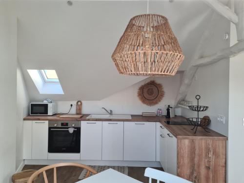 a kitchen with white cabinets and a chandelier at Santorin, Appartement lumineux au coeur de Vannes in Vannes