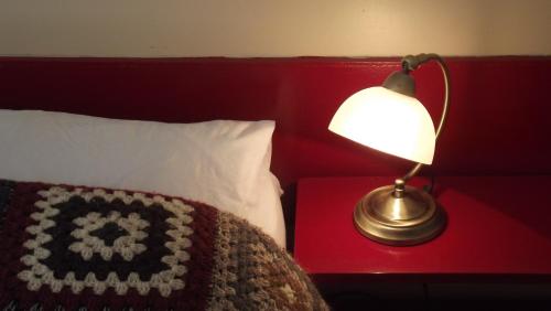 a lamp next to a bed with a red head board at Kilcommon Lodge Holiday Hostel in Belmullet