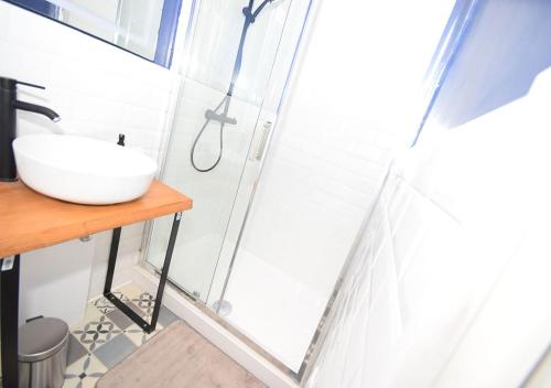 a bathroom with a sink and a glass shower door at COSY APPART - HYPER CENTRE - TRAMWAY - TERRASSE - leRelaisdOdile3 in Valenciennes