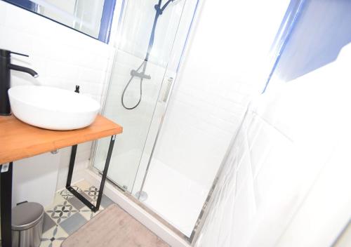 La salle de bains est pourvue d'un lavabo et d'une porte de douche en verre. dans l'établissement COSY APPART - HYPER CENTRE - TRAMWAY - TERRASSE - leRelaisdOdile3, à Valenciennes