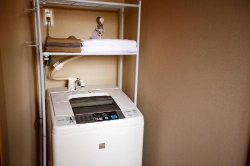 Fukumitsuにあるguesthouse絲 -ito-ゲストハウスイトの小さな部屋に洗濯機と乾燥機があります。