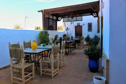 un patio con una mesa y algunas sillas, una mesa y un sillón en Dar Habache, en Marrakech