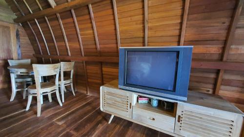 a television sitting on a stand in a room with a table at Villa Lumbung Salak in Bogor