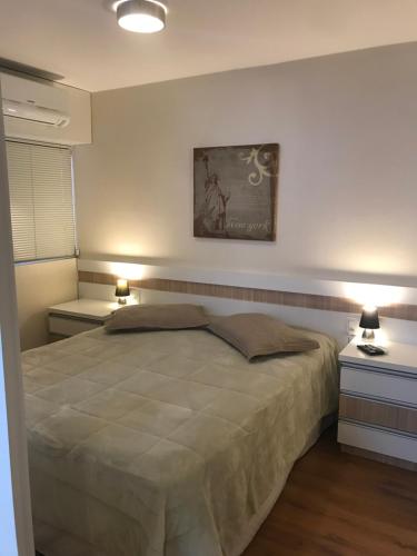 sypialnia z dużym łóżkiem i 2 szafkami nocnymi w obiekcie Wall Street Flat Service w mieście Caxias do Sul