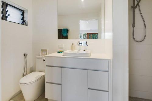 a white bathroom with a toilet and a sink at Woolloongabba, comfortable, modern, private studio in Brisbane