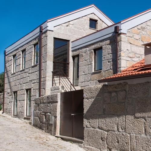 a stone house with a gate and a stone wall at Casa do Largo do Cruzeiro in Igarei