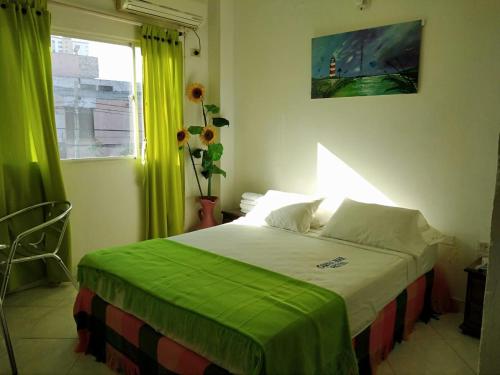 a bedroom with a bed with green curtains and a window at Blanco Mar Hotel in Santa Marta