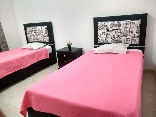 twee bedden in een kamer met roze lakens bij Familia Lombana in Bogota