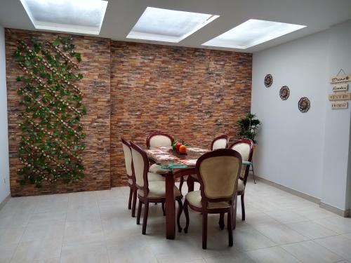 een eetkamer met een tafel en stoelen en een bakstenen muur bij Familia Lombana in Bogota