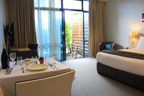 a hotel room with a bed and a table with wine glasses at Waves in Orewa