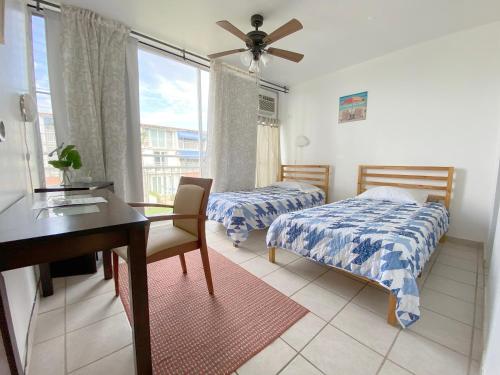 a bedroom with two beds and a desk and a window at Paradigm Villa Dorado in Dorado