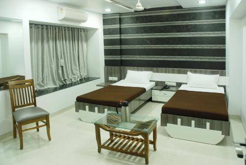 a bedroom with two beds and a chair at Hotel City View in Navi Mumbai