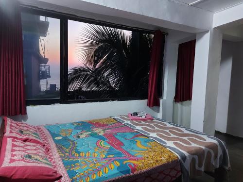 a bed in a room with a large window at Red Rock Arambol Beach in Arambol