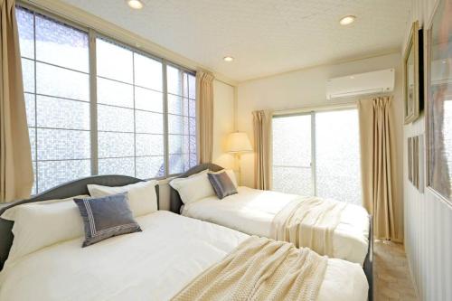 two beds in a room with large windows at Meee Shinjuku in Tokyo