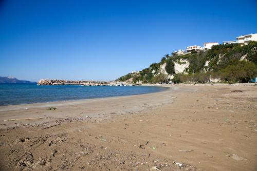 a sandy beach with buildings on a hill next to the water at Meandros in Almirida