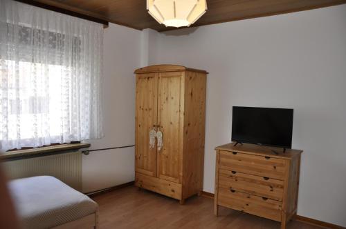 um quarto com uma televisão e um armário de madeira em Super zentral und dennoch idyllisch und erholsam em Dreieich