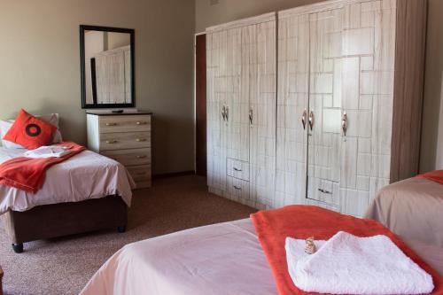 a bedroom with two beds and a dresser with a mirror at Gemstone Guest House in Klerksdorp